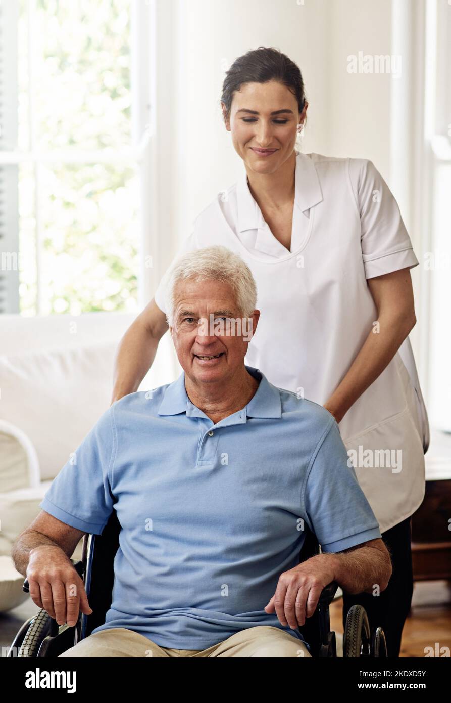 HES in guten Händen. Porträt eines lächelnden Betreuers und eines älteren Mannes in einem Rollstuhl zu Hause. Stockfoto