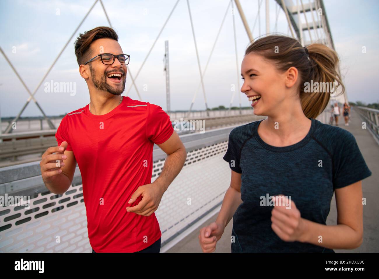 Workout am frühen Morgen. Glückliches Paar, das über die Brücke läuft. Ein gesunder Lebensstil. Stockfoto