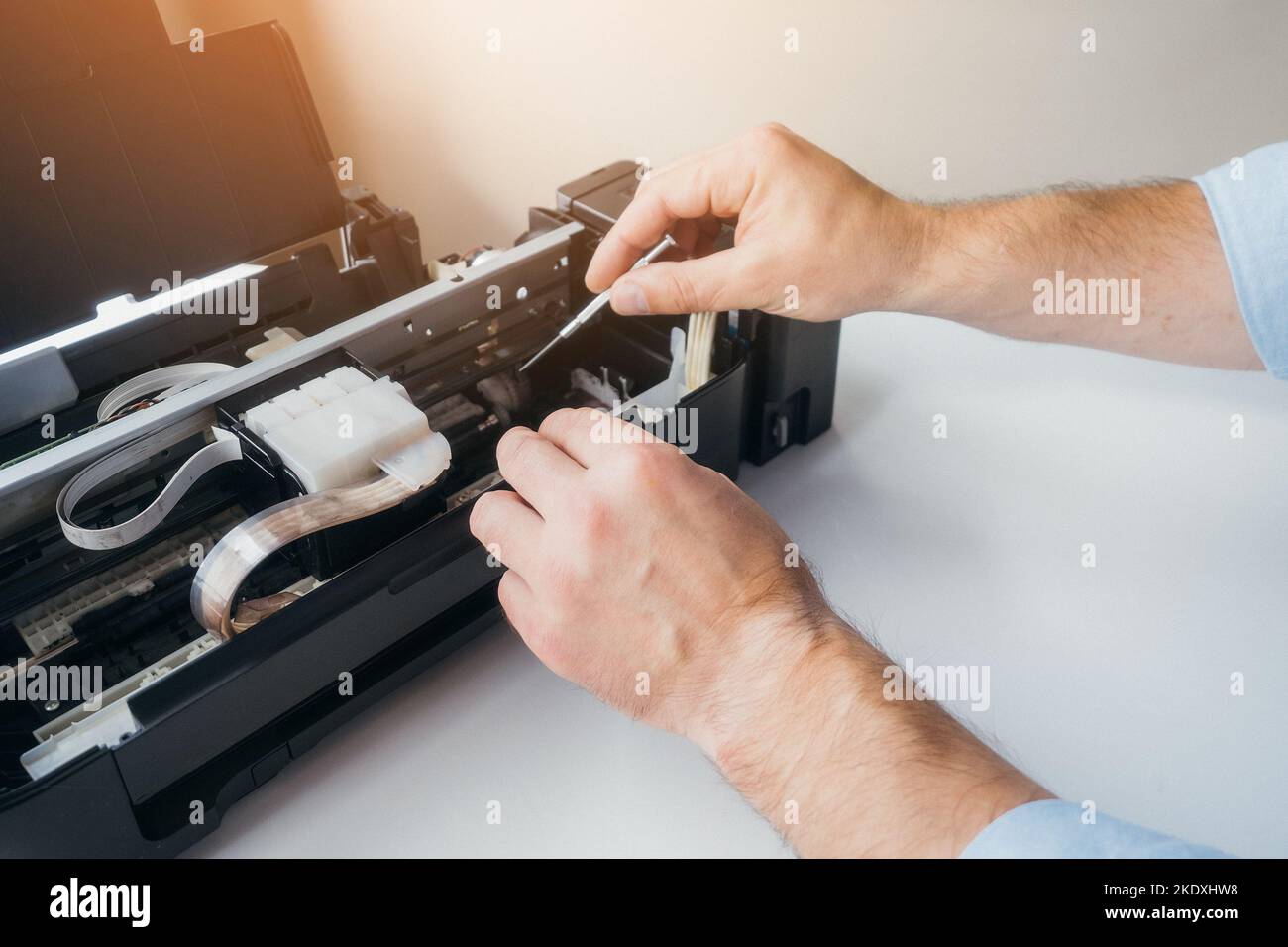 Wartung und Reparatur von Druckern. Hände des Meisters mit Schraubendreher. Hintergrund. Dringende Reparatur von Bürogeräten zu Hause oder im Büro. Stockfoto