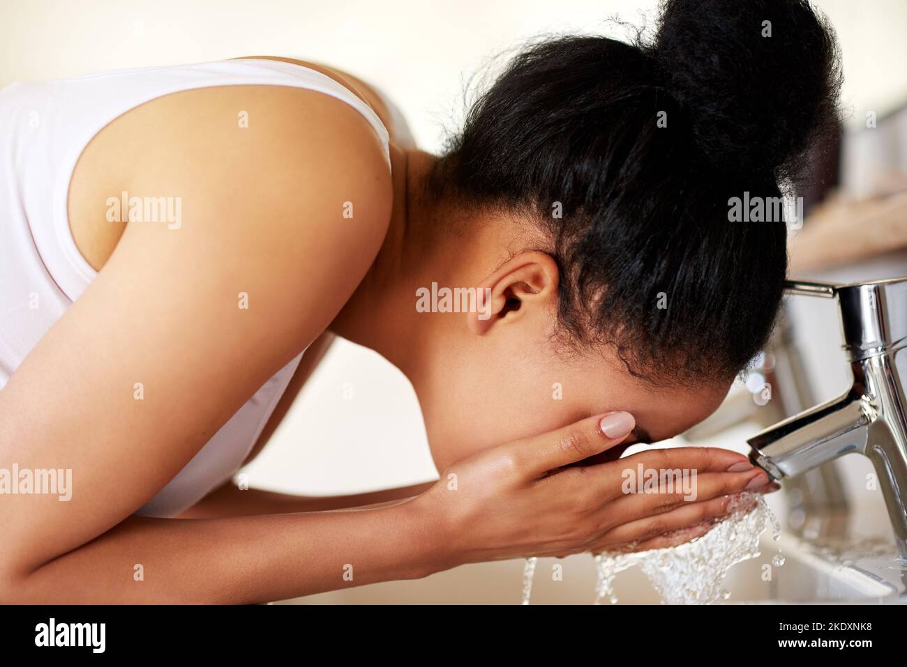 Ihre Haut mit der Liebe zu behandeln, die sie verdient. Eine junge Frau wäscht ihr Gesicht am Waschbecken im Badezimmer. Stockfoto