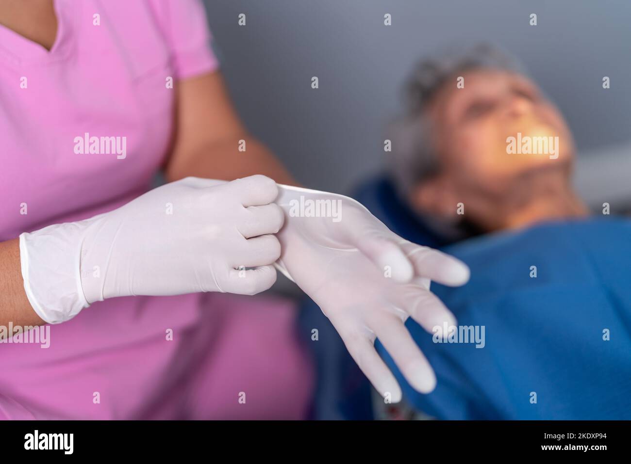 Von oben der Ernte unkenntlich weibliche Zahnarzt setzen auf Latexhandschuhe in der Nähe von älteren Patienten vor dem Eingriff in der modernen Zahnklinik Stockfoto