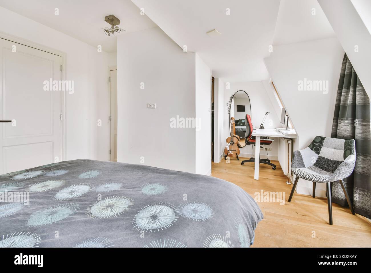 Stilvolle, einfache Innenausstattung des Schlafzimmers mit weißer Wand und schwarzem Bett unter weißer Decke mit Balken Stockfoto
