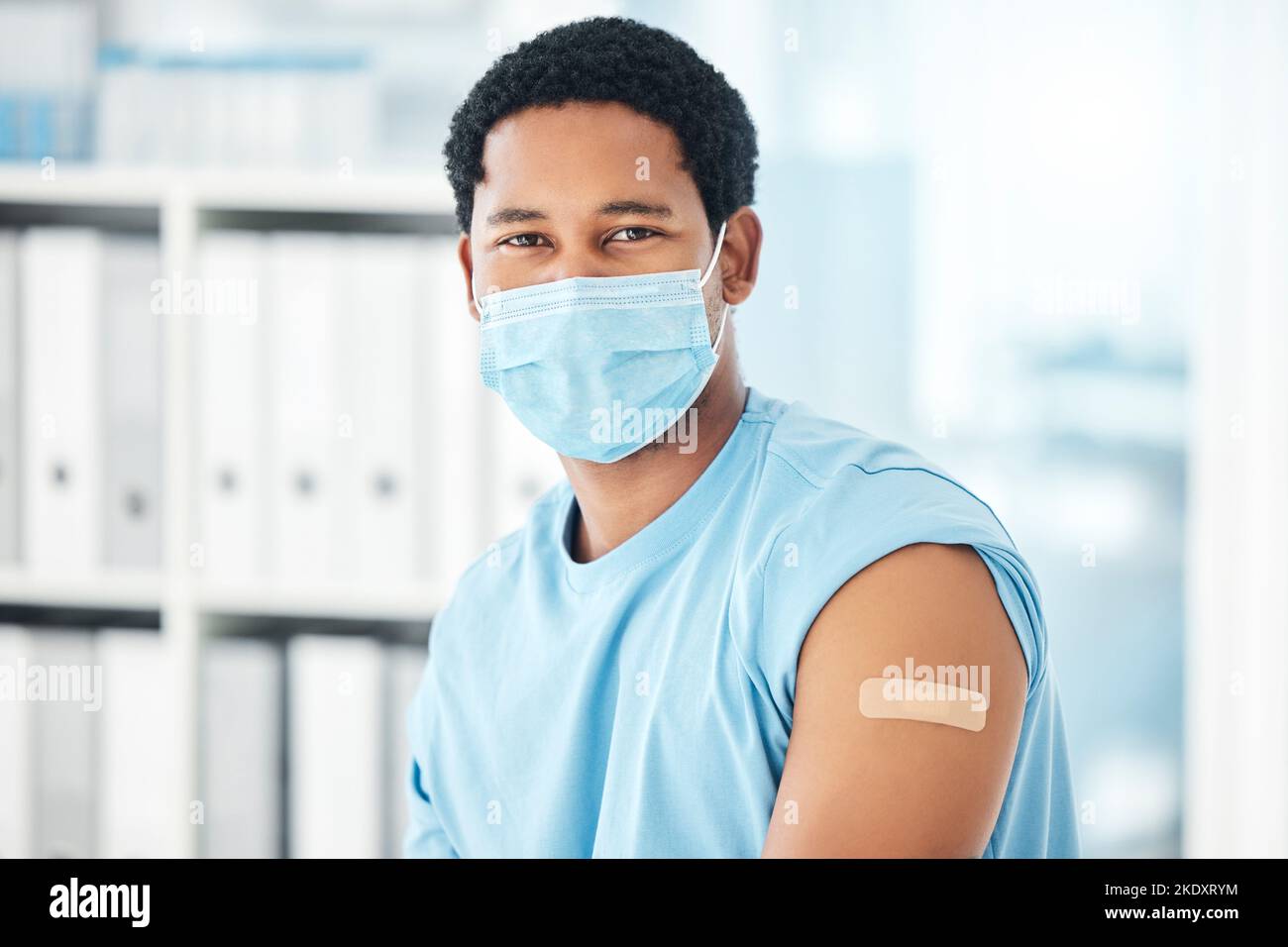 Maske, Impfstoff und Mann mit Gips im Krankenhaus zur Einhaltung der Gesundheitsvorschriften. Junge gesunde afrikanische Patienten, Kliniksicherheit und Corona Prävention oder Stockfoto