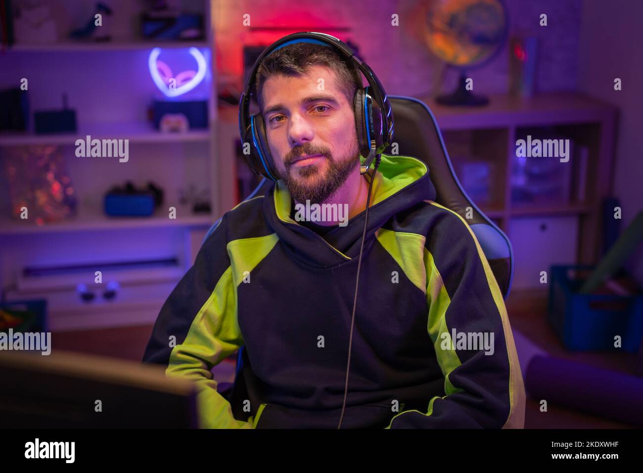 Gamer-Portrait mit farbenfrohen Neon-LED-Leuchten, die auf die Kamera blicken. Stockfoto