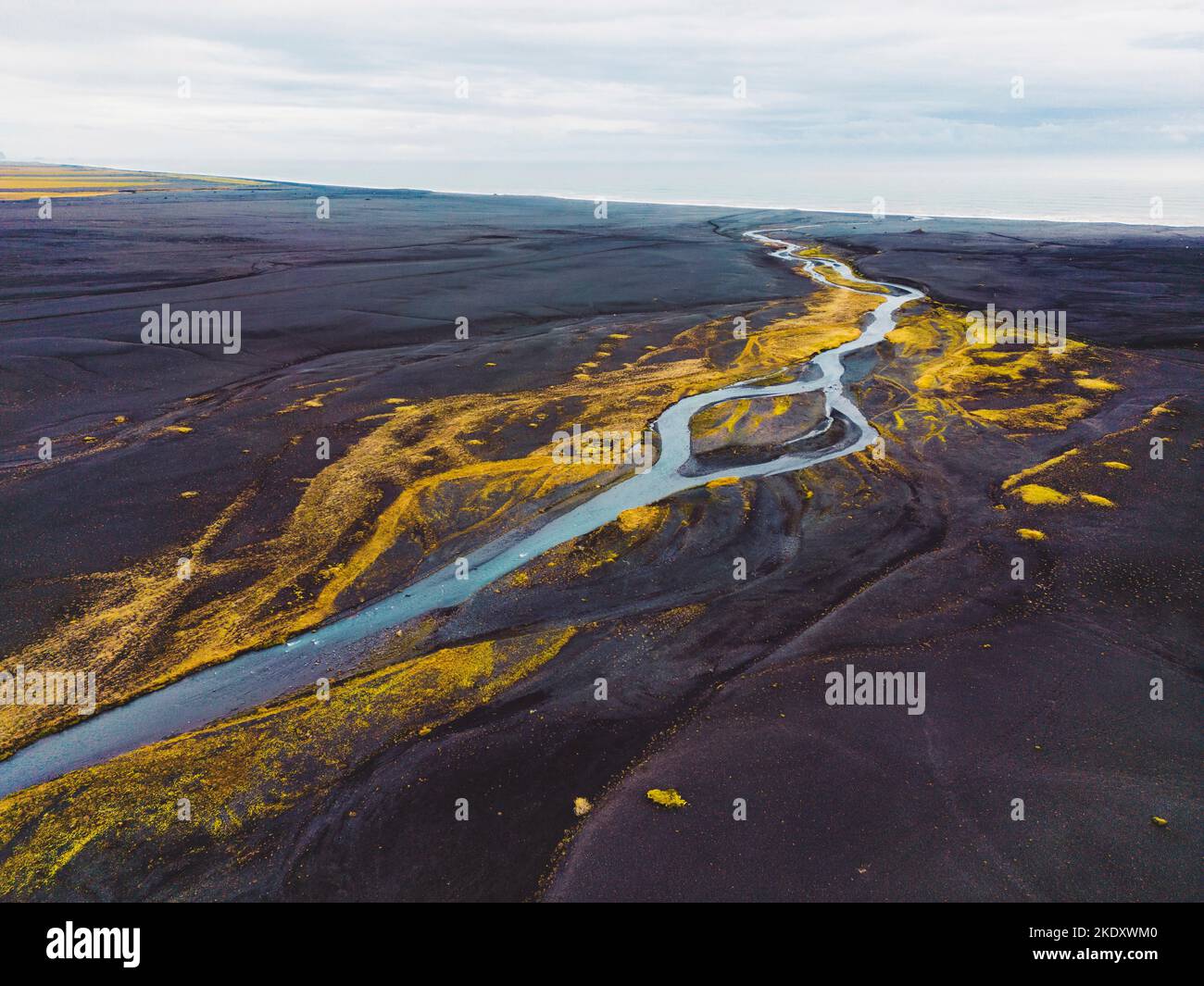 Ein Fluss, der durch den schwarzen Sandstrand von Selheimasandur fließt Stockfoto