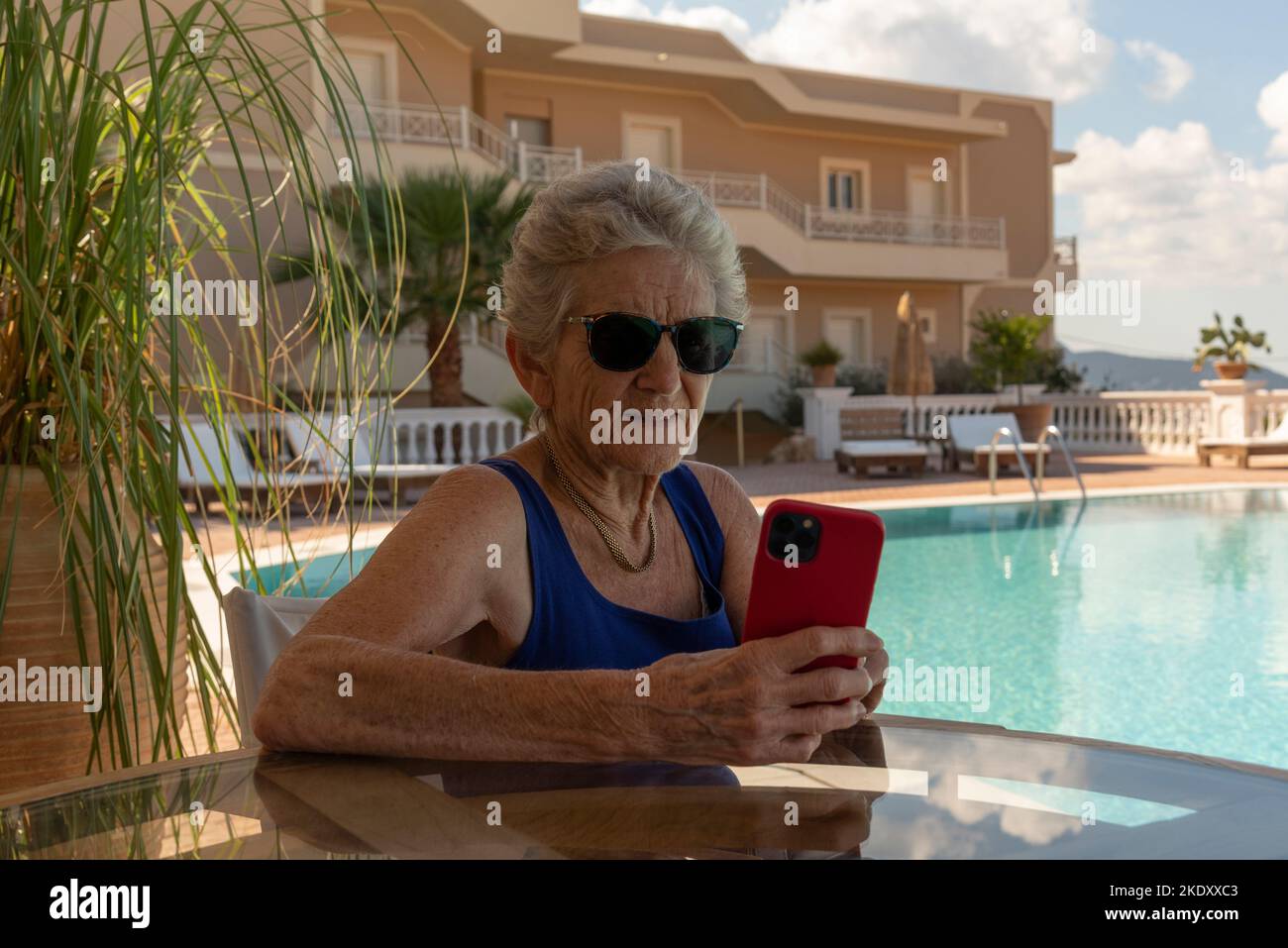 Kreta Griechenland.2022. Ältere Frau, die ein Mobiltelefon am Hotelpool benutzt. Stockfoto