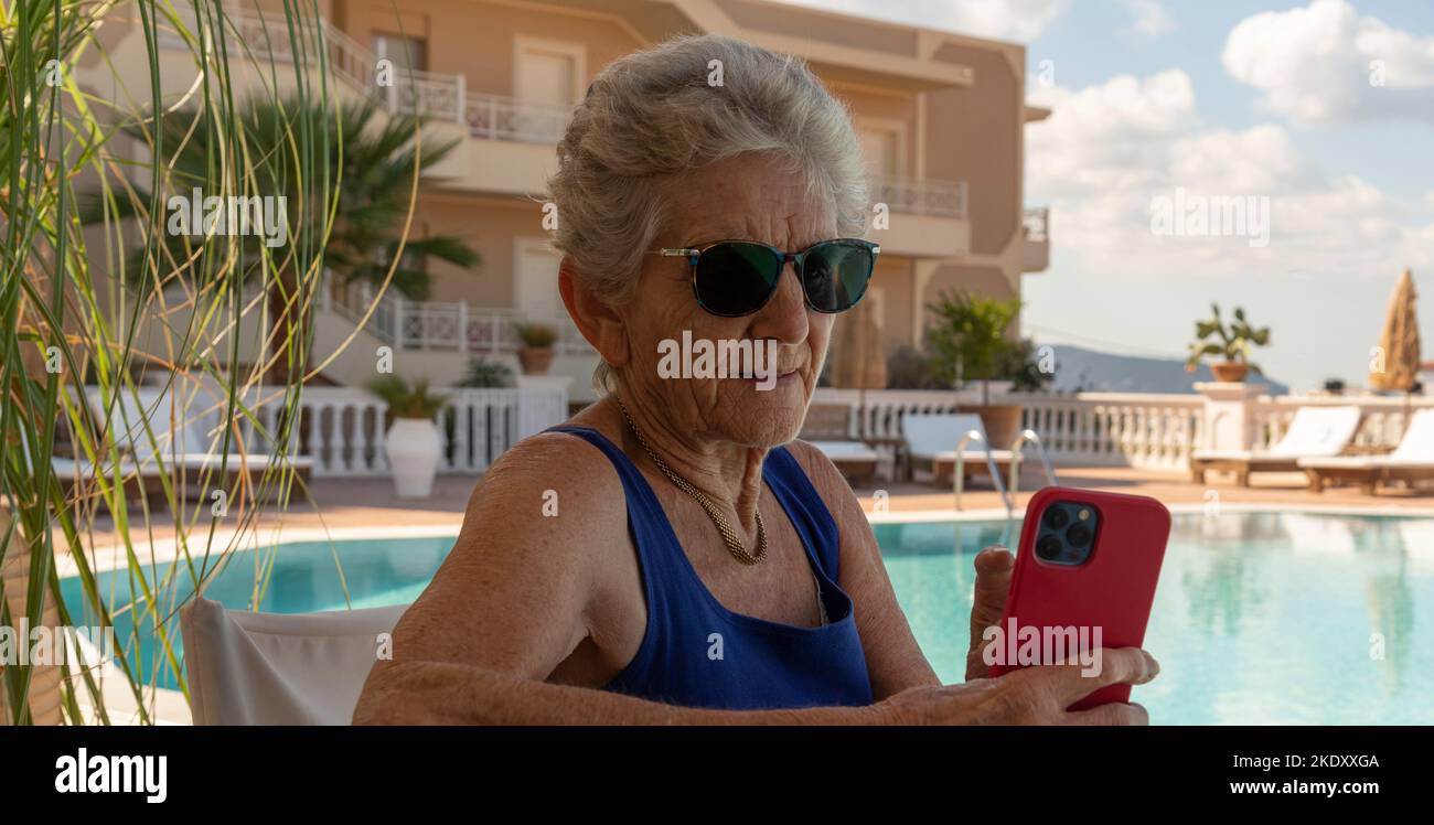 Kreta Griechenland.2022. Ältere Frau, die ein Mobiltelefon am Hotelpool benutzt. Stockfoto
