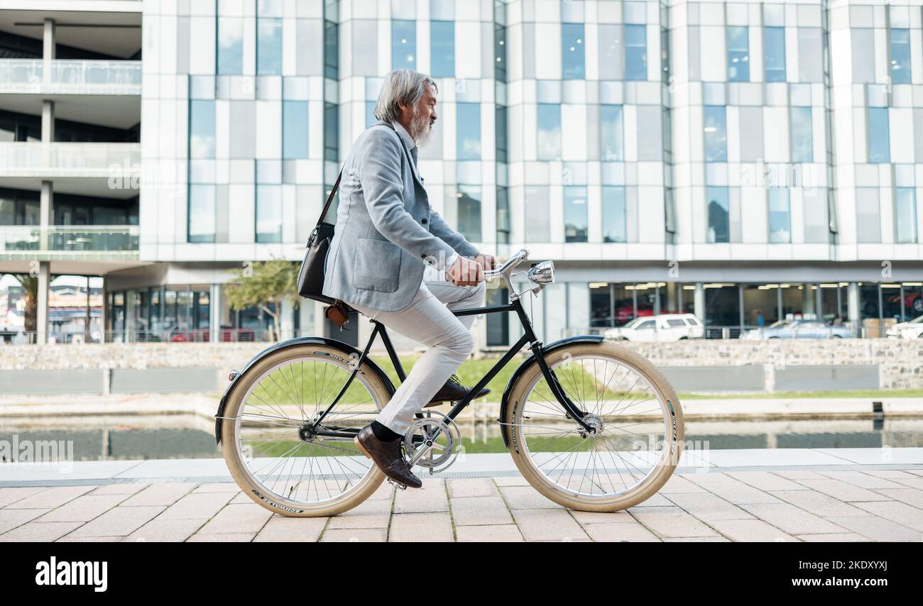 Reise-, Stadt- und asiatische Geschäftsmann auf dem Fahrrad, Radfahren, um in der Stadt zu arbeiten, um einen geringen CO2-Fußabdruck zu erreichen. Nachhaltigkeit, Transport und Seniorenreiten Stockfoto