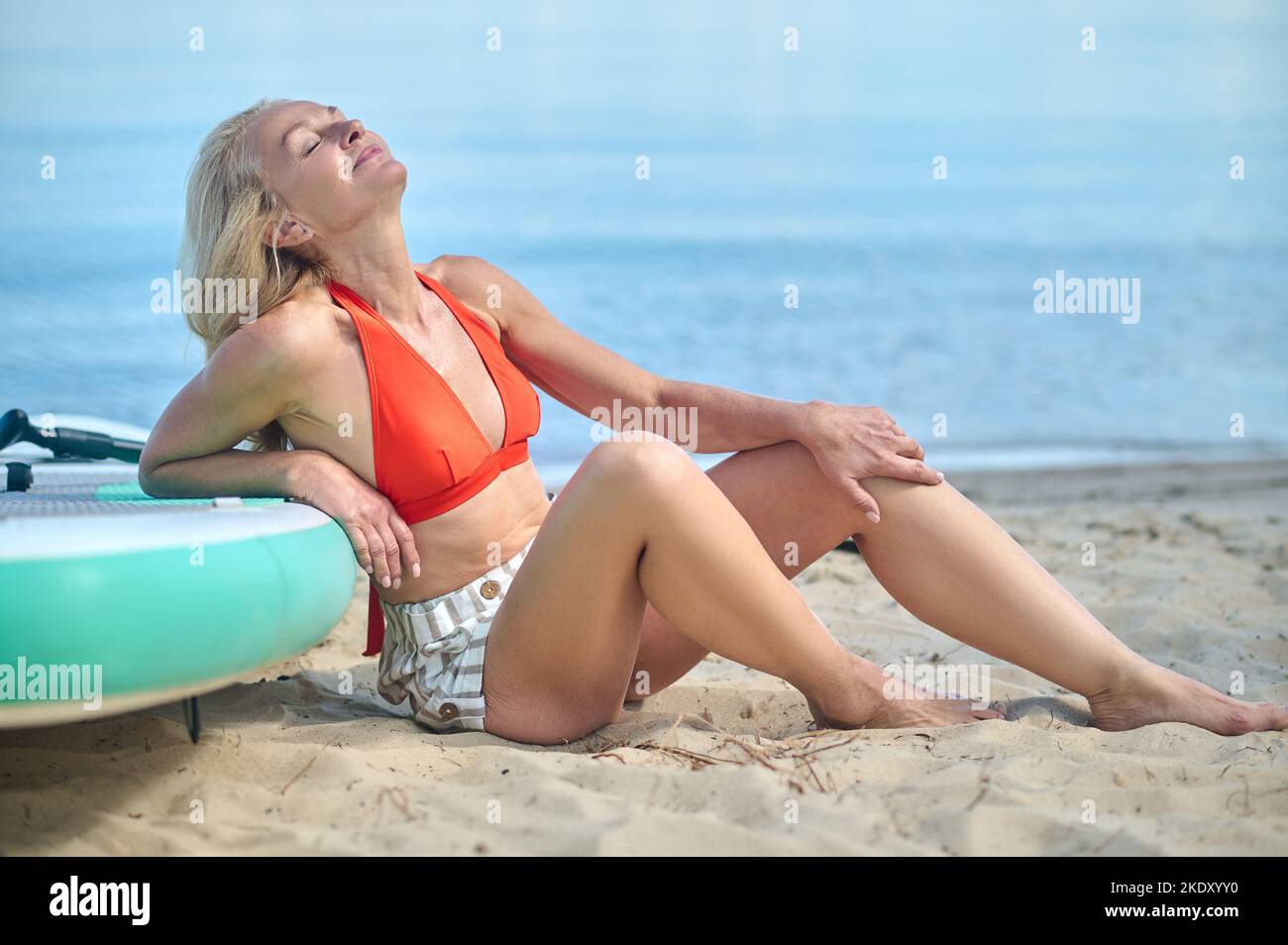 Nette reife Frau, die das sonnige Wetter am Strand genießt Stockfoto