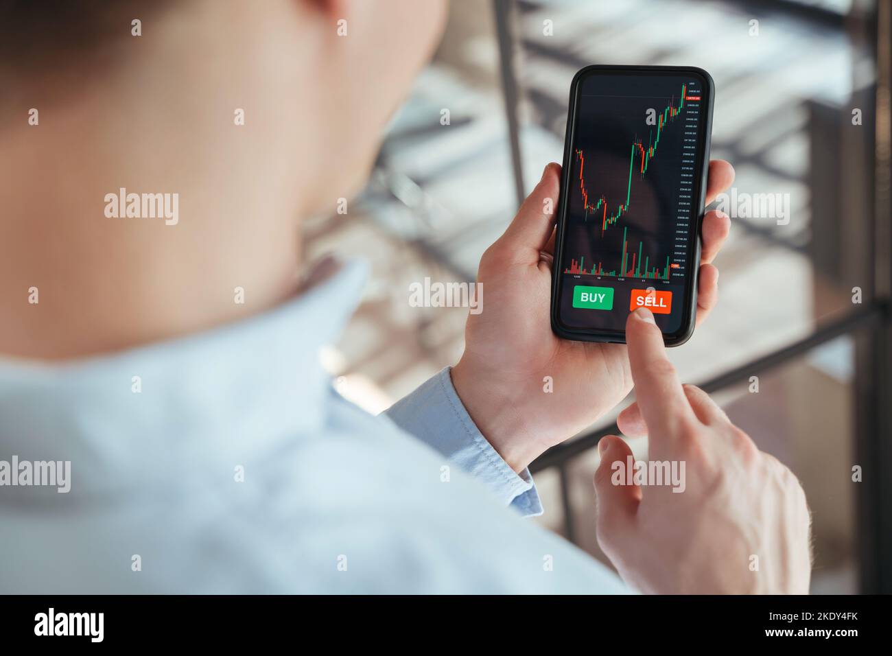 Nahaufnahme kein Gesichtsbild des Traders, der mit der Kryptowährungs-App die Sell-Taste auf dem Smartphone drücken wird, nachdem er die Börsenmarkt- oder Kryptowährungsdaten analysiert und das Smartphone in den Händen gehalten hat Stockfoto