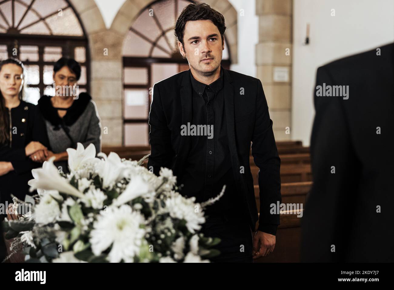 Beerdigung, Tod und Trauer mit einem Mann, der während einer Zeremonie einen Sarg in einer Kirche trug. Blumen, Anzug und Verlust mit einem Männchen, das eine Schatulle hält Stockfoto