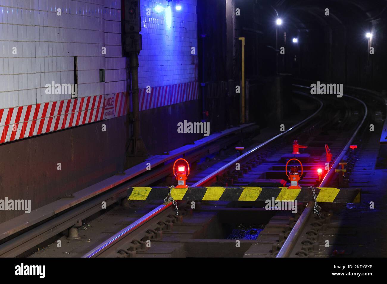 Eine gelb gestreifte Barrikade, die an einen Abschnitt der NYC-U-Bahn-Strecke mit Warnleuchten und tragbaren Reisegeräten als Teil sicherer Arbeitsverfahren gekettet ist Stockfoto