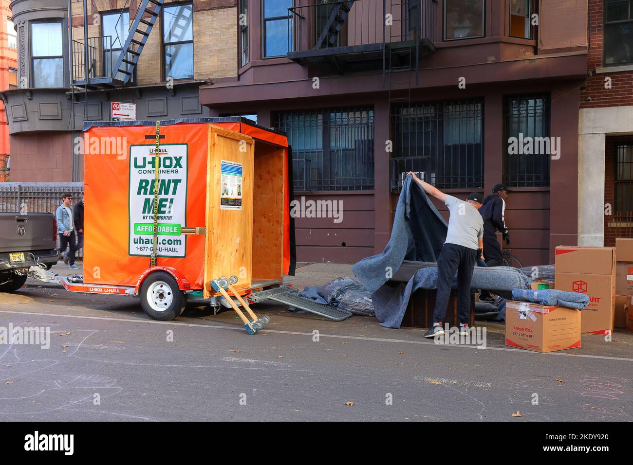 Personen, die einen U-Haul U-Box-Mietlagercontainer vor einem Apartmentgebäude verpacken. Stockfoto
