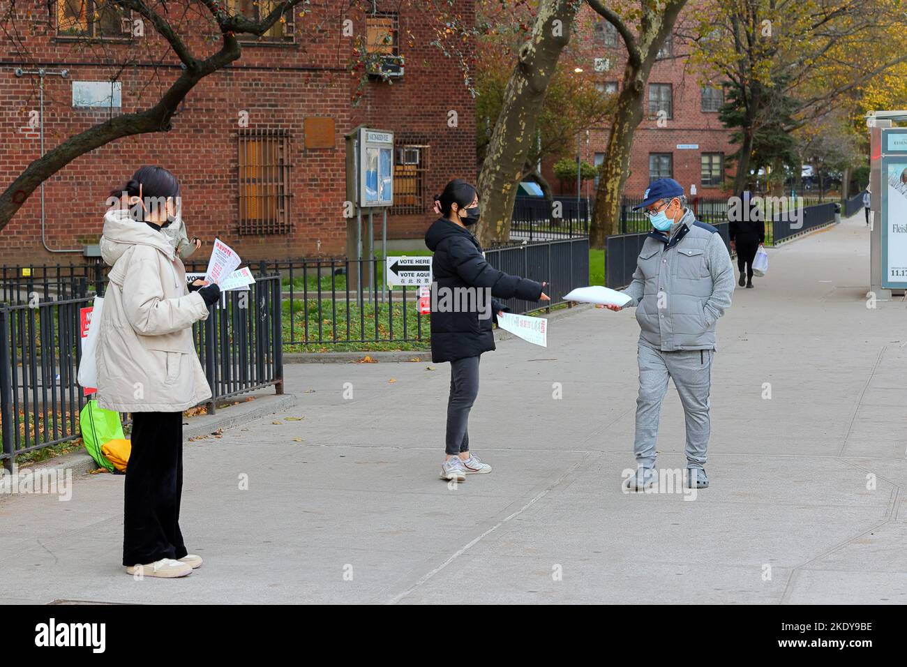 Zwei Chinesisch-amerikanische Frauen mit mehrsprachigen Begleitblättern, die vor einem Wahllokal in Manhattan Chinatown, New York, am 8. November 2022 Wahlkampf veranstalteten Stockfoto
