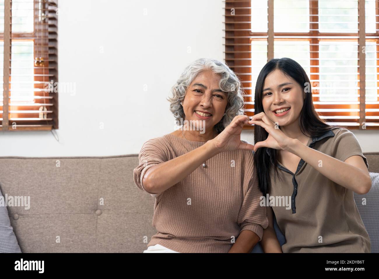 Lächelnd Erwachsene Tochter umarmt ältere Mutter. Zwei Generationen Konzept, schöne junge Frau umarmt reife Frau, posiert für Foto zusammen. Stockfoto