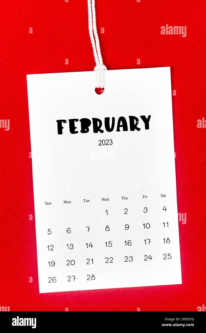Kalenderseite Februar 2023 für 2023 Jahre an weißem Seil auf rotem Hintergrund gehängt. Stockfoto