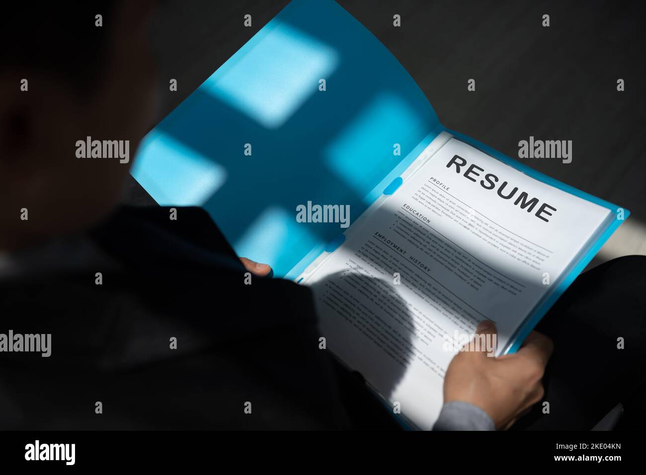 Arbeitsloser Mann bewerben sich für einen Job in der Warteschlange mit Lebenslauf Papiere warten auf Vorstellungsgespräch mit Sonnenlicht und Schatten sitzen. Stockfoto