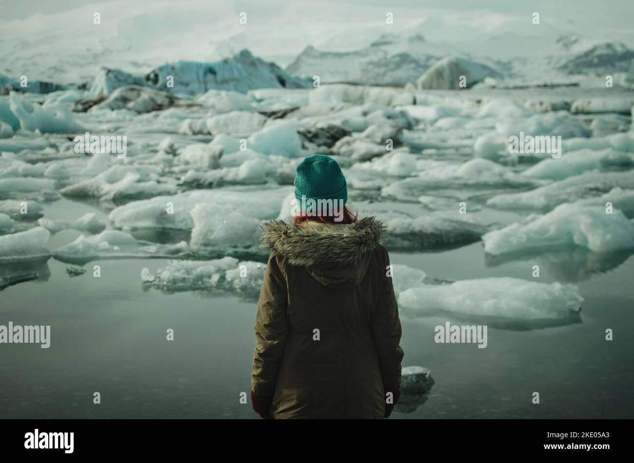 Eine Frau, die einen Parka trägt, steht vor der Jökulsárlón-Gletscherlagune in Island Stockfoto