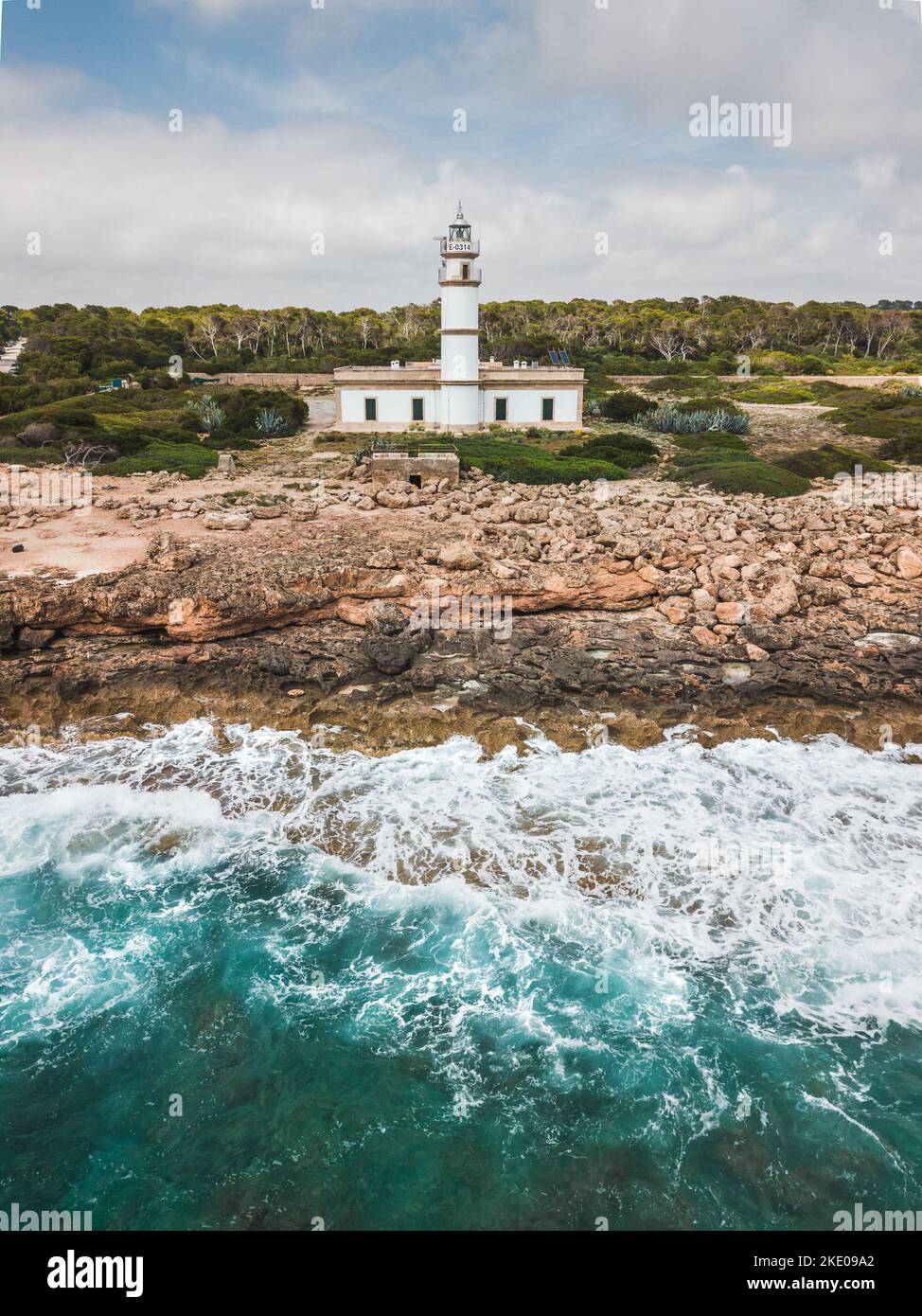 Der Leuchtturm an einem felsigen Ufer vom Cap de ses Salines in Spanien Stockfoto