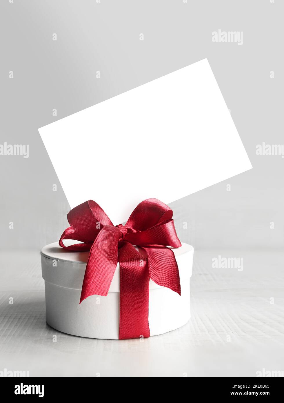 Runde Geschenkbox mit rotem Band und Schleife auf grauem Hintergrund. Stockfoto