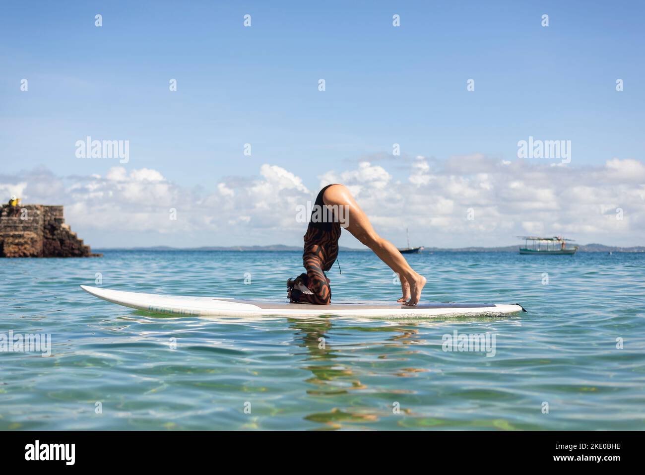 Eine Frau, die auf einem Surfbrett am Strand von Porto da Barra in Salvador, Bahia, steht. Stockfoto