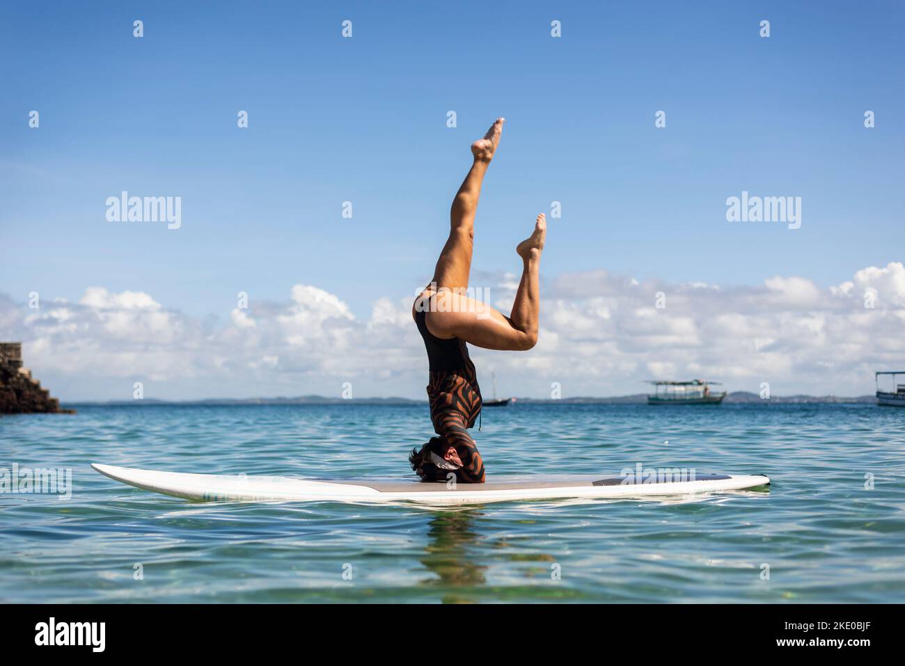 Eine Frau, die auf einem Surfbrett am Strand von Porto da Barra in Salvador, Bahia, steht. Stockfoto
