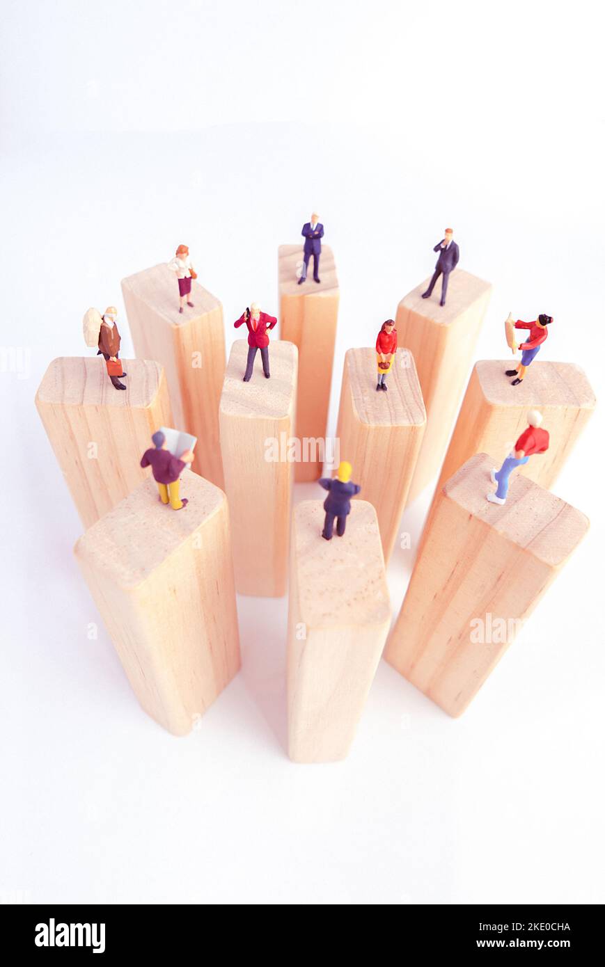Draufsicht auf Miniaturspielzeug, das auf Holzblock steht - soziales Distanzierungskonzept, antisoziales oder Teamwork-Konzept. Stockfoto