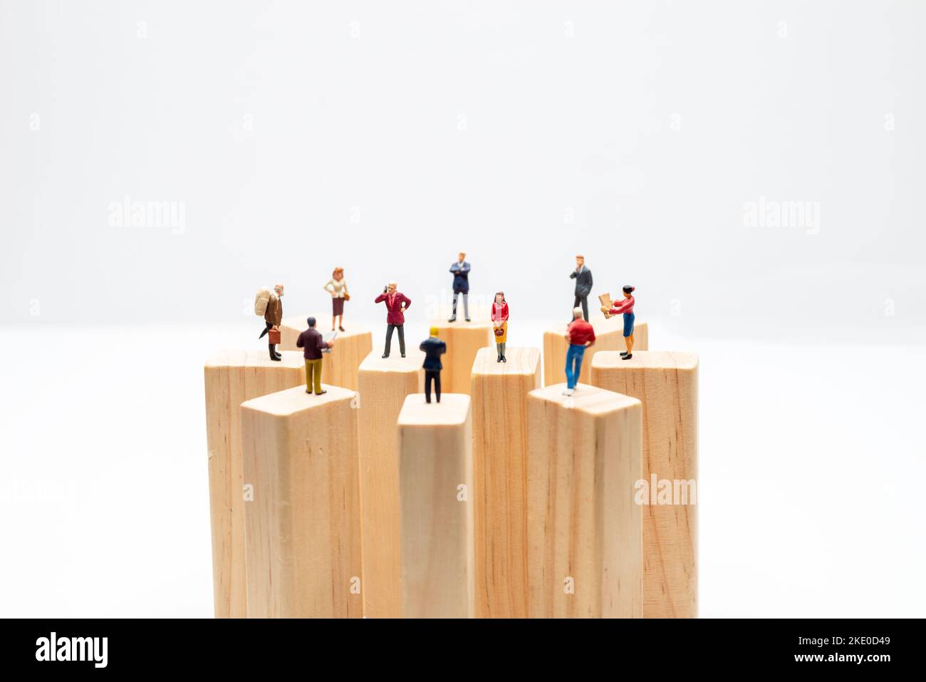 Miniaturspielzeuge, die auf Holzklotz stehen - soziale Distanzierung, anti-soziales Konzept oder Teamarbeit. Stockfoto