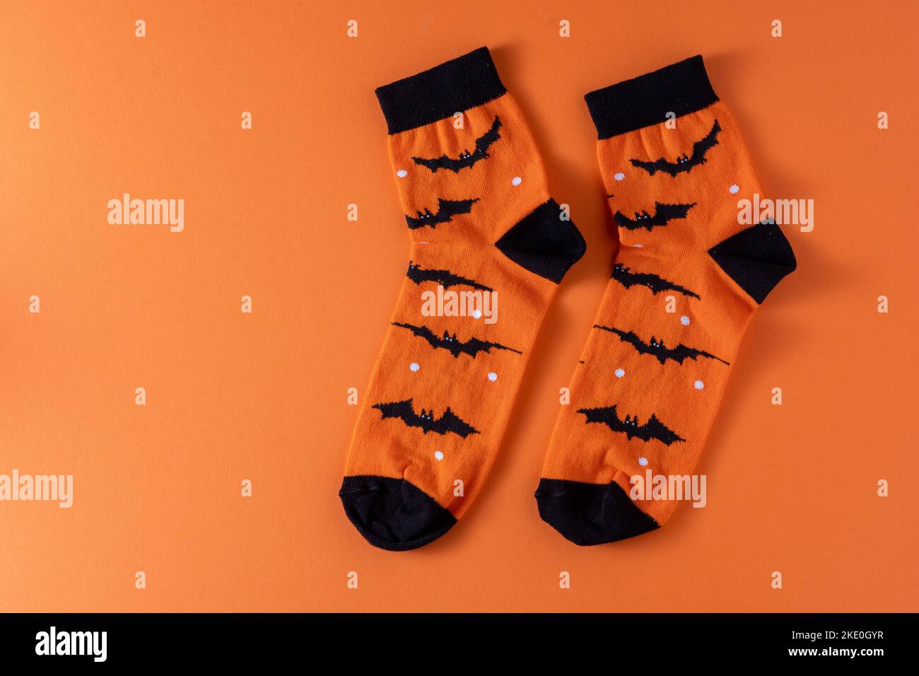 Orangefarbene Socken mit Fledermäusen. Kleidung Kostüm für Halloween-Party. Fröhliche helle mehrfarbige Socke Draufsicht. Speicherplatz kopieren. Stockfoto