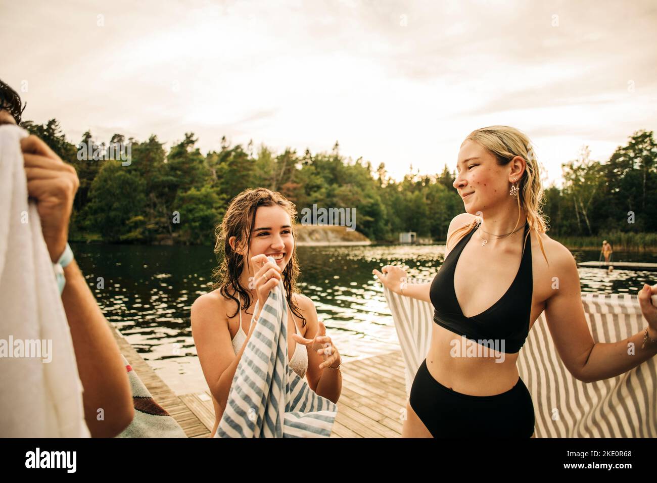 Frauen mit Handtuch reden während des Urlaubs am See miteinander Stockfoto