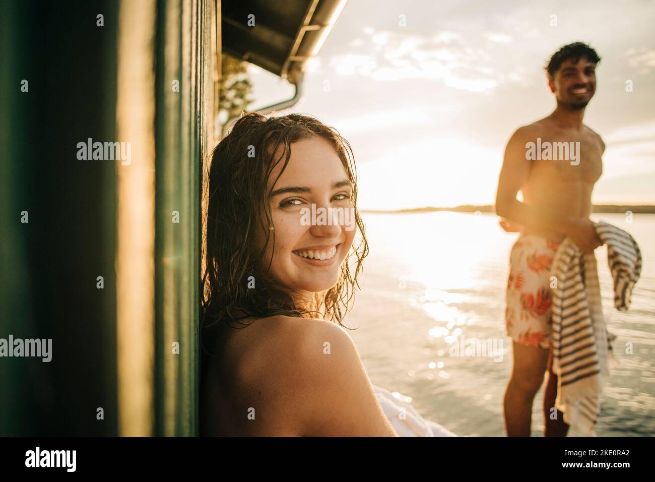 Porträt einer glücklichen Frau, die während des Urlaubs bei Sonnenuntergang über die Schulter schaut Stockfoto