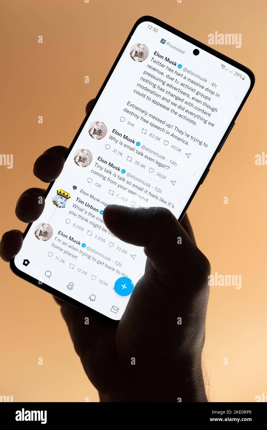 New york, USA - 4. November 2022: Elon Musk Tweets auf Smartphone lesen, das auf braunem Hintergrund isoliert in der Hand gehalten wird Stockfoto