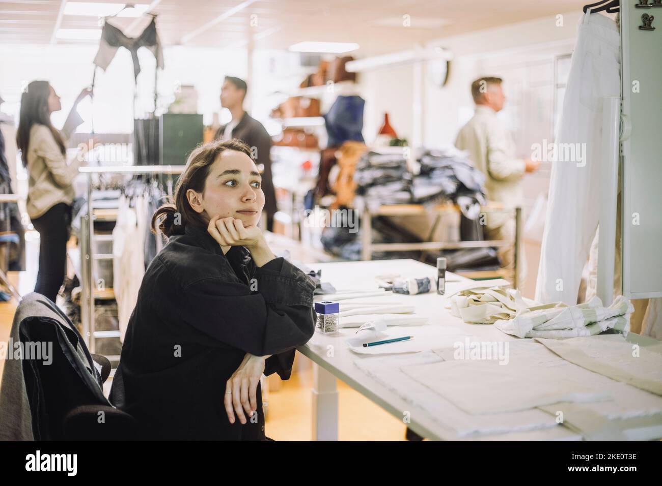 Nachdenkliche Modedesignerin mit Hand am Kinn im Workshop Stockfoto