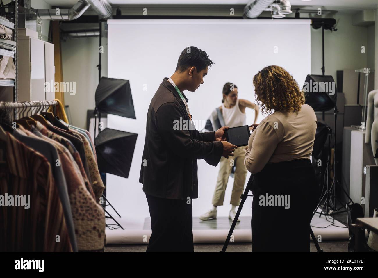 Seitenansicht eines männlichen Designers, der im Studio mit einer Fotografin diskutiert Stockfoto