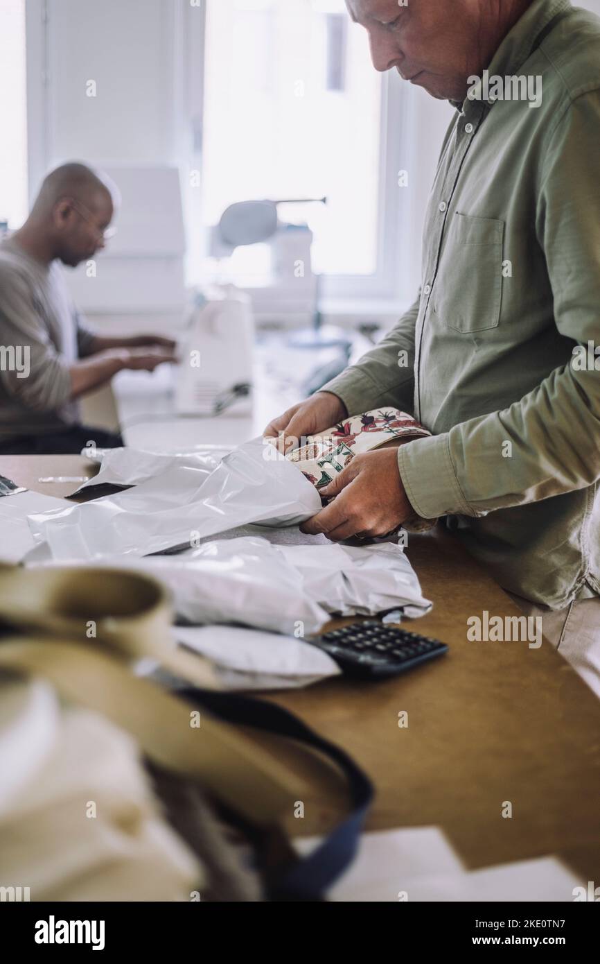 Männlich Mode Designer Verpackung Stoff während der Arbeit in der Werkstatt Stockfoto