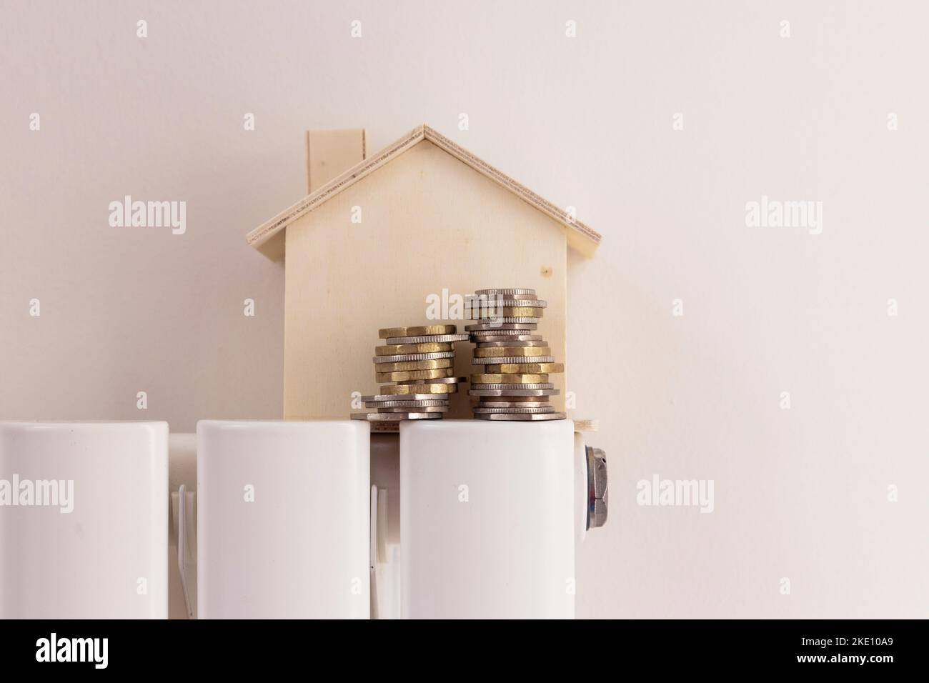 Lebenshaltungskosten der Haushalte. Geld und ein Hausmodell auf einem Heizkörper Stockfoto