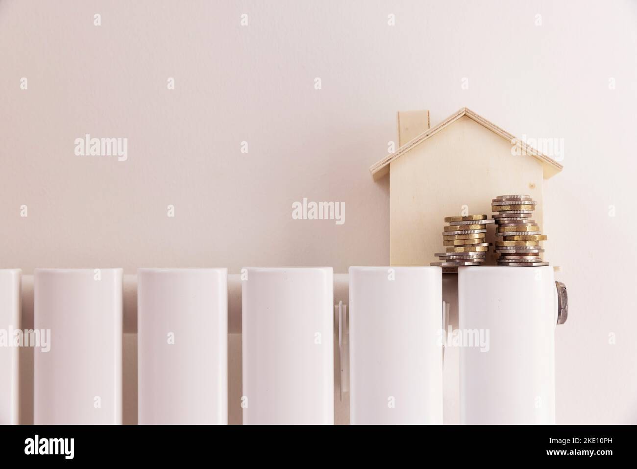 Lebenshaltungskosten der Haushalte. Geld und ein Hausmodell auf einem Heizkörper Stockfoto