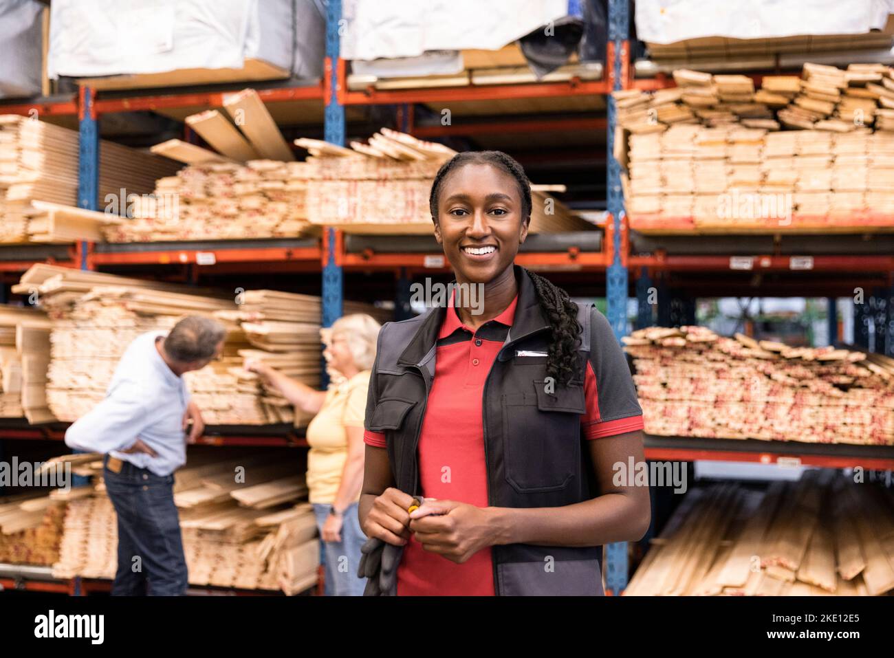 Porträt einer lächelnden Verkäuferin, die vor dem Regal im Baumarkt steht Stockfoto