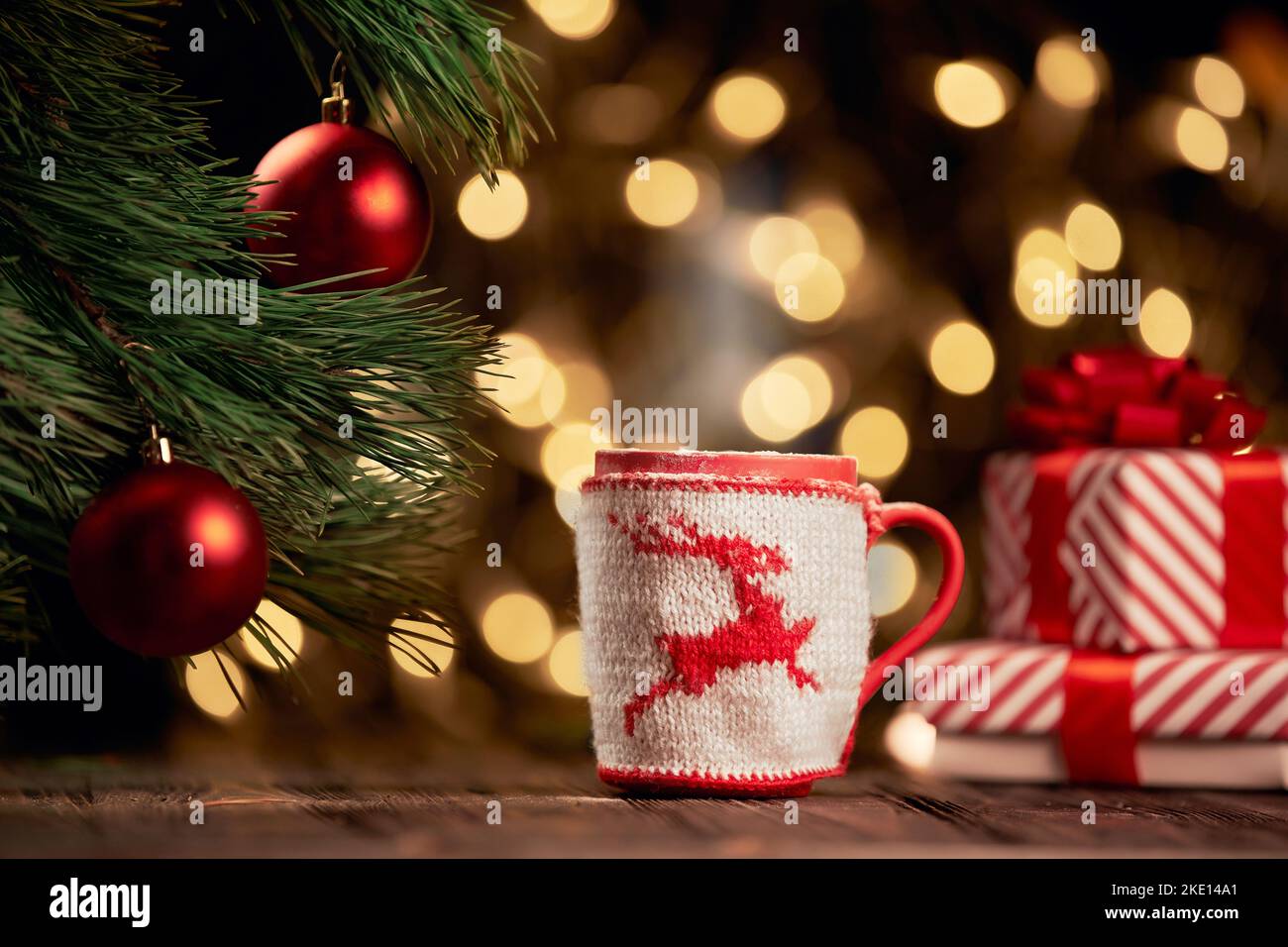 becher mit Weihnachtsschmuck und Schachteln mit Geschenken auf festlichem Hintergrund. Stockfoto
