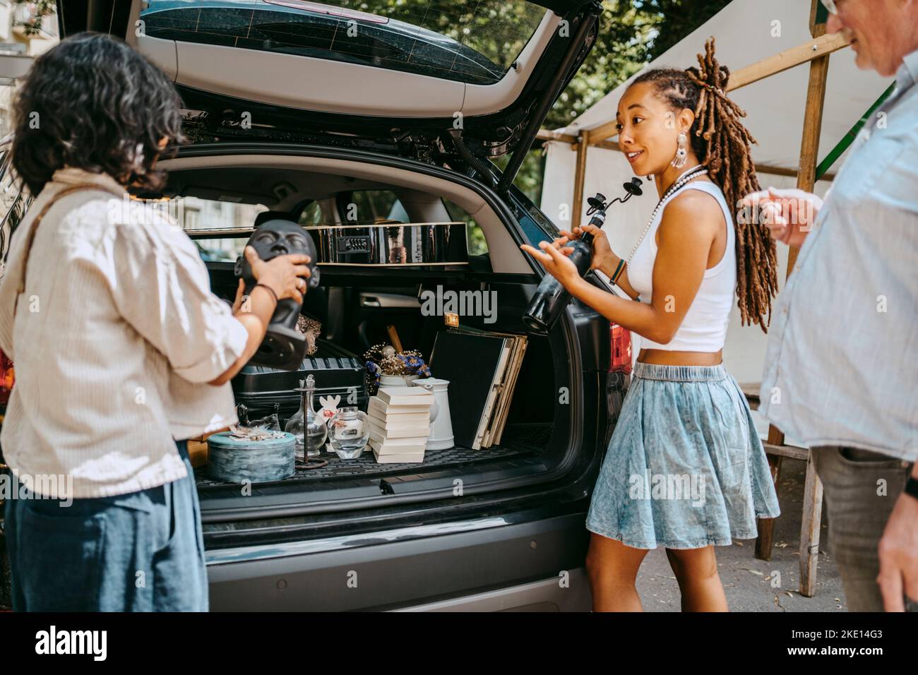 Frauen sprechen miteinander, während sie Waren auf dem Flohmarkt in den Kofferraum laden Stockfoto