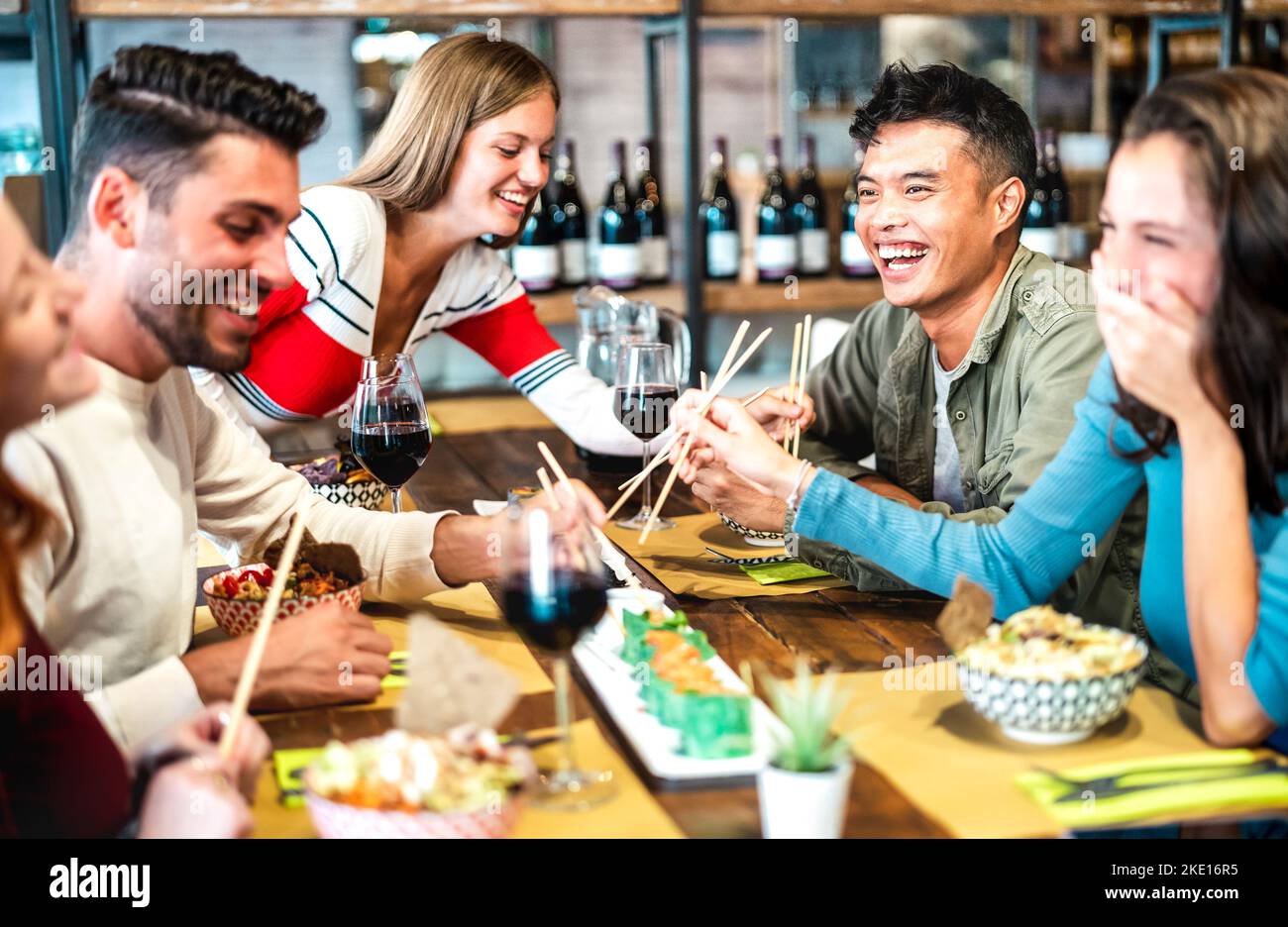 Multikulturelle, trendige Freunde, die Sushi mit Essstäbchen in der Fusion Restaurant Bar essen - Lebensstilkonzept für Speisen und Getränke mit glücklichen jungen Menschen Stockfoto