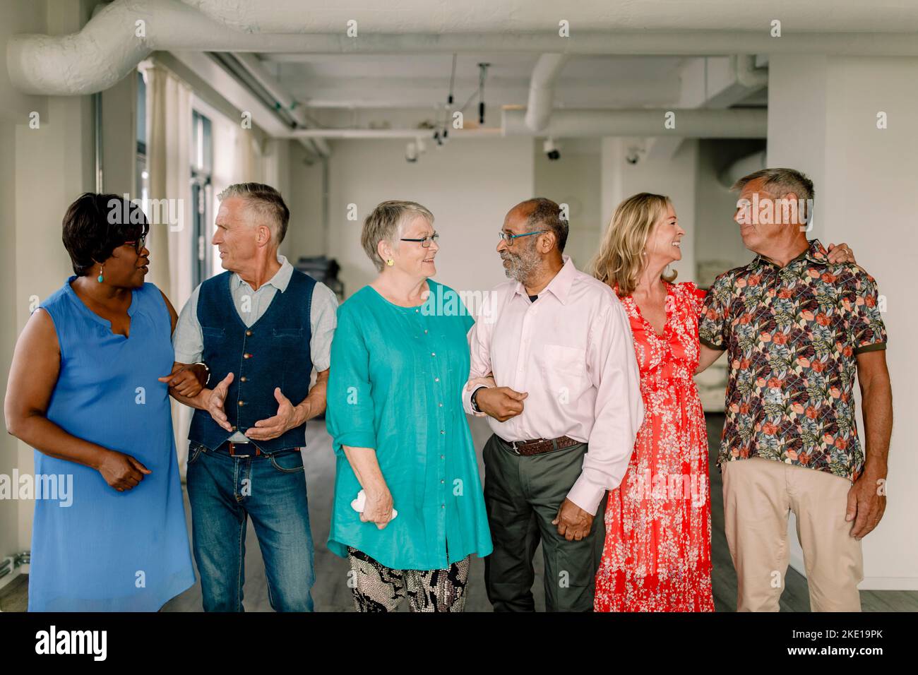 Lächelnde, multirassische Senioren-Paare, die sich im Tanzunterricht gegenseitig anschauten und sich unterhielten Stockfoto