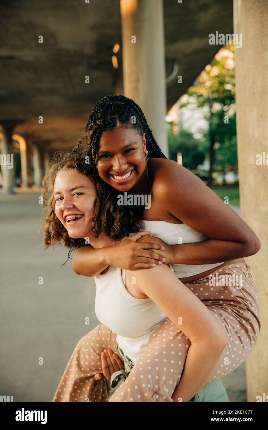 Porträt von glücklichen Teenager-Mädchen geben Huckepack Fahrt zu weiblichen Freund Stockfoto