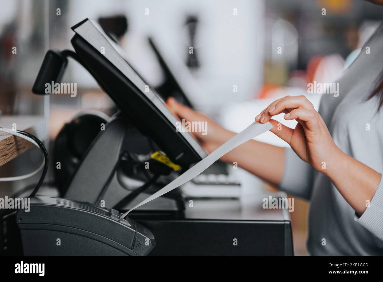 Verkäuferin druckt Rechnung oder Beleg für einen Kunden im Einkaufszentrum, POS-System, Finanzkonzept Stockfoto
