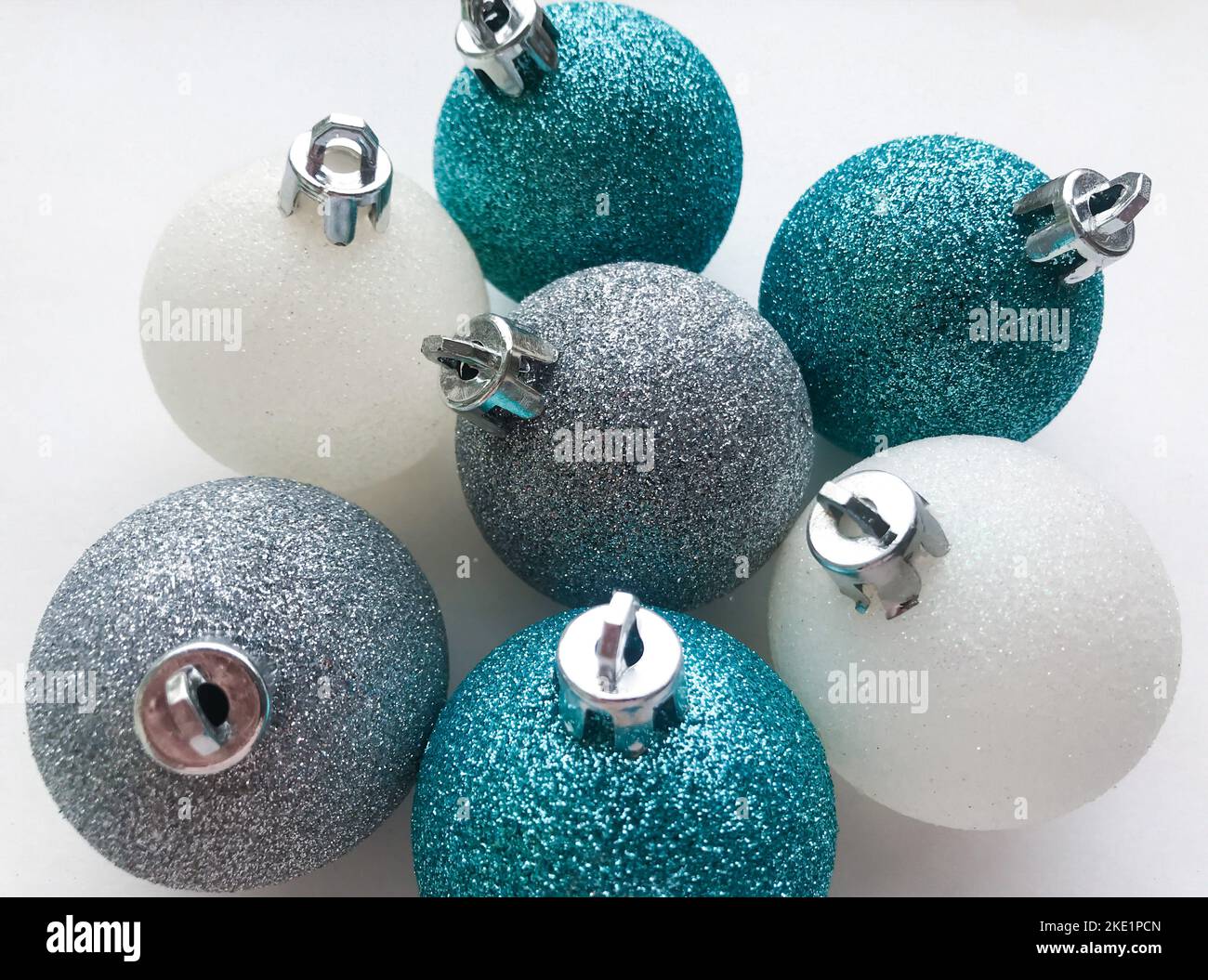 Nahaufnahme von glänzenden Weihnachtskugeln blau türkis, weiß, silber auf weißem Hintergrund. Das Konzept von Weihnachten und Neujahr. Stockfoto