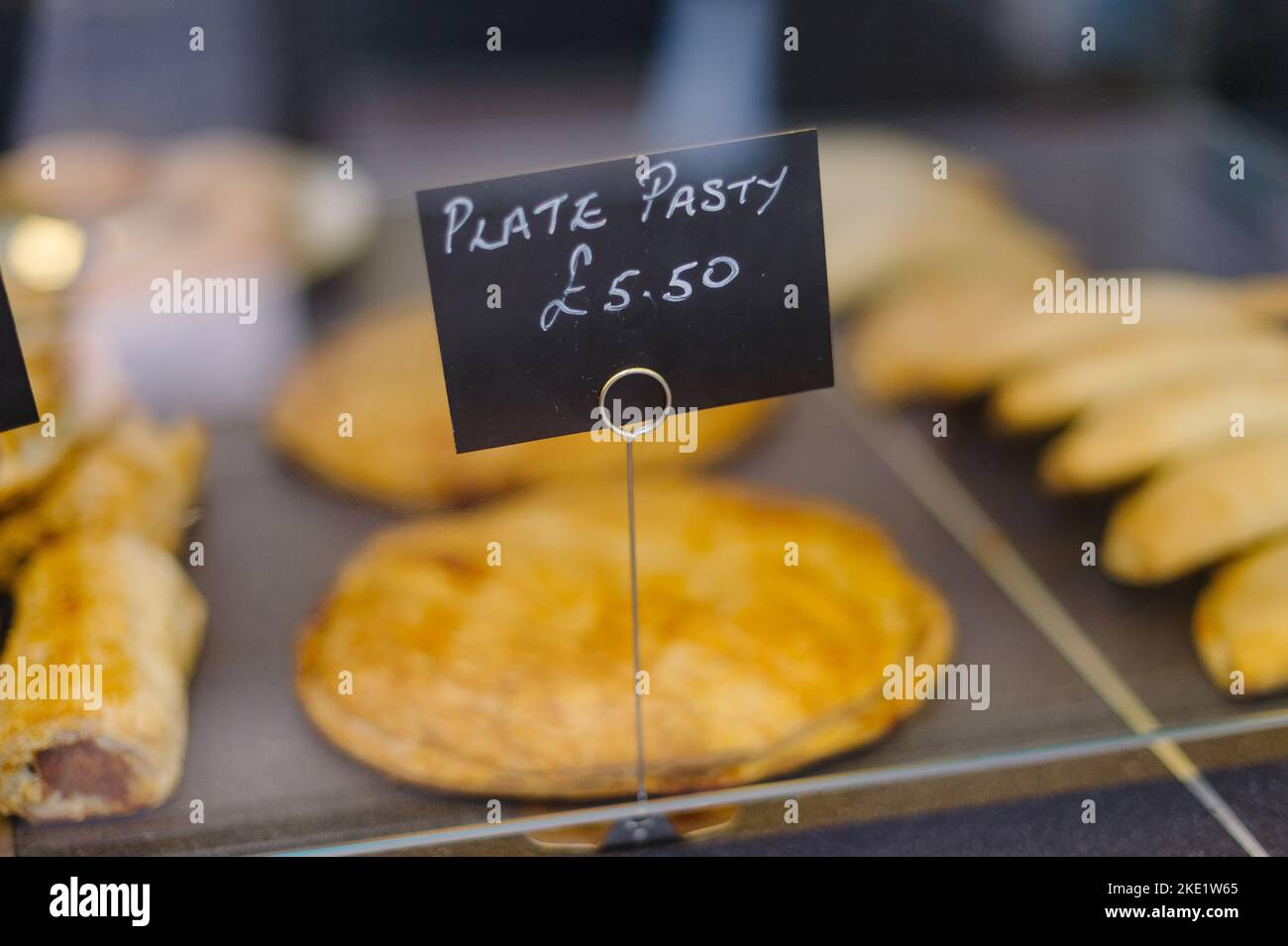 Pies und Pasties zum Verkauf in einer Bäckerei, Hände halten einen Kuchen Stockfoto