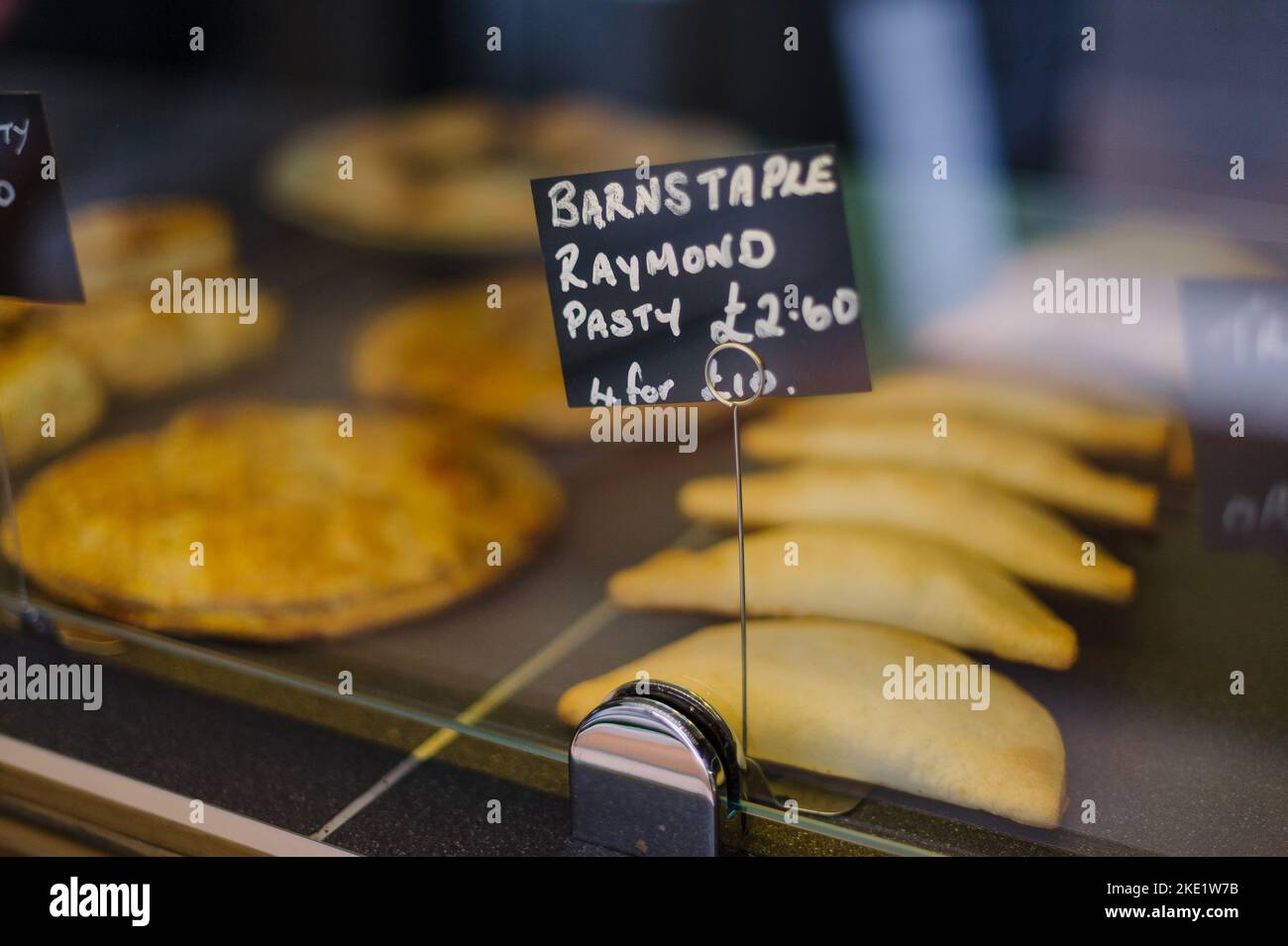 Pies und Pasties zum Verkauf in einer Bäckerei, Hände halten einen Kuchen Stockfoto