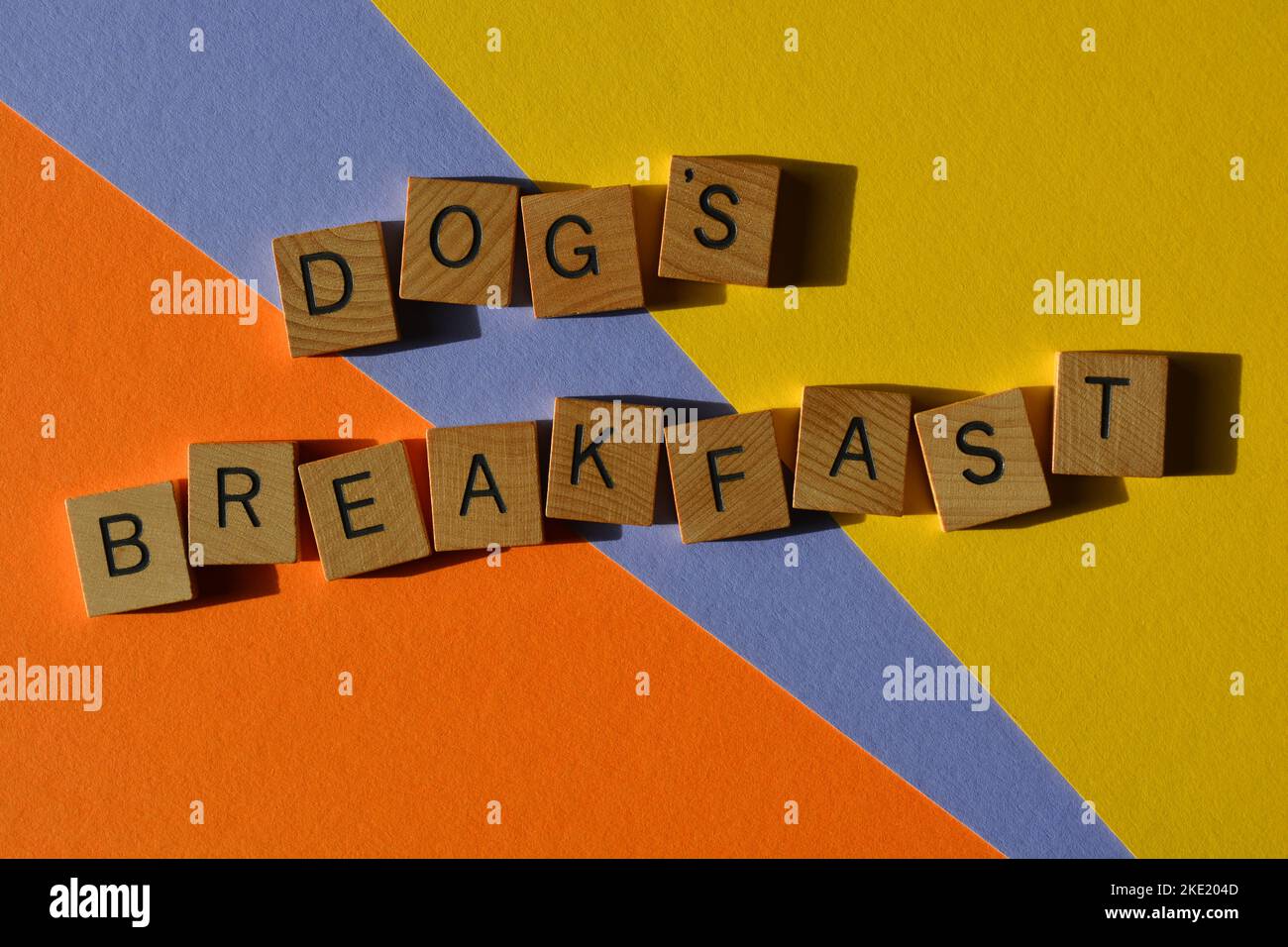 Dog's Breakfast, australischer Slang-Satz, der ein totales Chaos in hölzernen Buchstaben bedeutet, die auf farbenfrohem Hintergrund isoliert sind Stockfoto