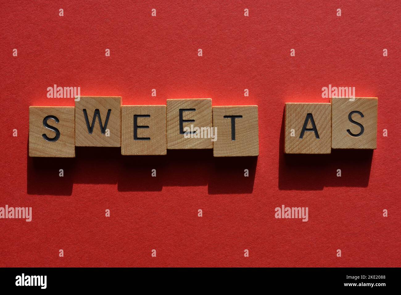 Sweet as, australischer Slang für ehrfürchtig oder gut in hölzernen Buchstaben isoliert auf rotem Hintergrund Stockfoto
