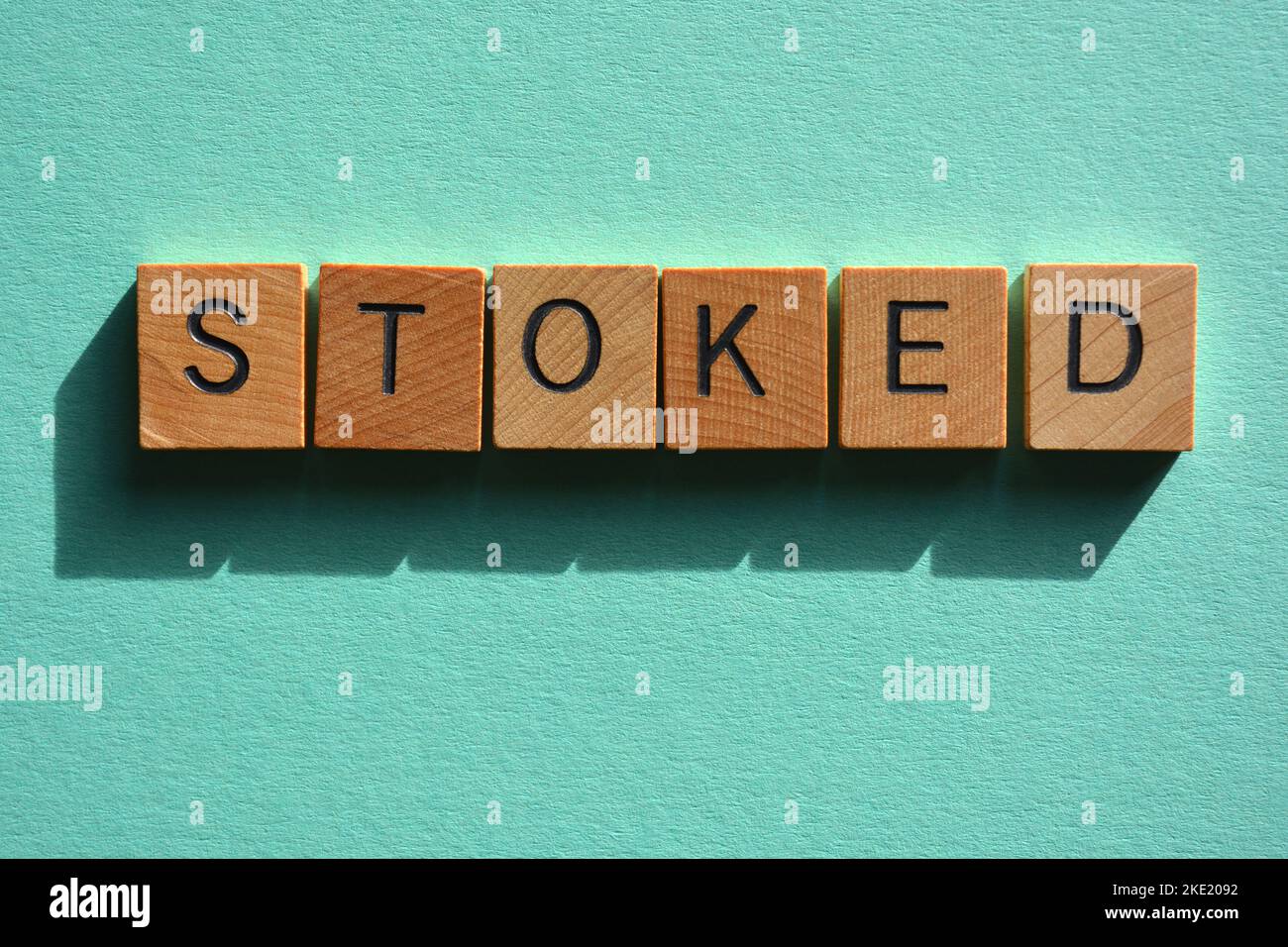 Stoked, Australian Slang Wort Bedeutung erfreut in hölzernen Buchstaben Alphabet isoliert auf Hintergrund Stockfoto